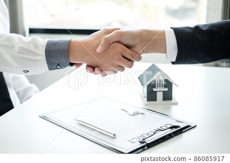 Businessmen and brokers' real estate agents shake hands after completing negotiations to buy houses insurance and sign contracts. Home insurance concept 86085917