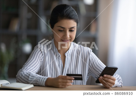 Happy young Indian woman shopping in internet store. 86086910