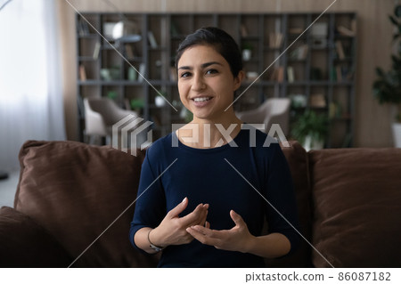 Happy young Indian woman talking holding web camera call. Happy young Indian woman talking holding web camera call. 86087182