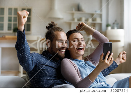 Laughing young family couple celebrating internet success. 86087254