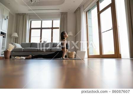Calm woman practicing yoga at home, consulting online video lesson 86087607