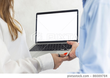 A man and a woman are holding an open laptop with a white screen mockup A man and a woman are holding an open laptop with a white screen mockup 86089784