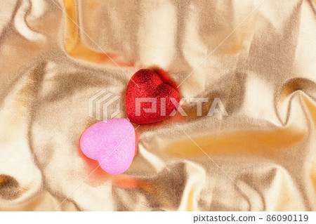 Two hearts red and pink lie on a golden background Two hearts red and pink lie on a golden background 86090119