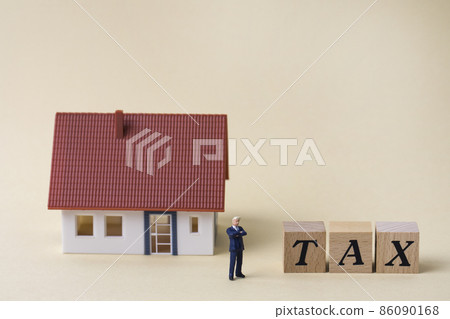 Cube with house and miniature man and tax written on it 86090168