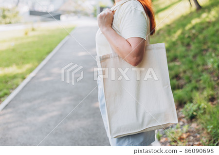 Happy young Woman with white cotton bag in her hands. Mockup and zero waste concept. Eco Nature Friendly Style. Environmental Conservation Recycling mock up Happy young Woman with white cotton bag in her hands. Mockup and zero waste concept. Eco Nature Friendly Style. Environmental Conservation Recycling mock up 86090698