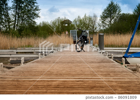 Wood plank boat dock with a bicycle parked during a bike ride around Arendsee lake in Germany 86091809