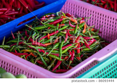 Green and red chili in the plastic basket for sale at fresh market. Green and red chili in the plastic basket for sale at fresh market. 86093444