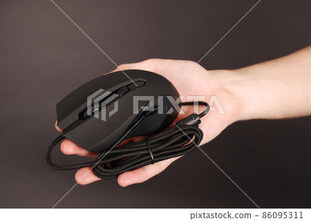 Man holds in his hand black computer optical mouse Man holds in his hand black computer optical mouse 86095311