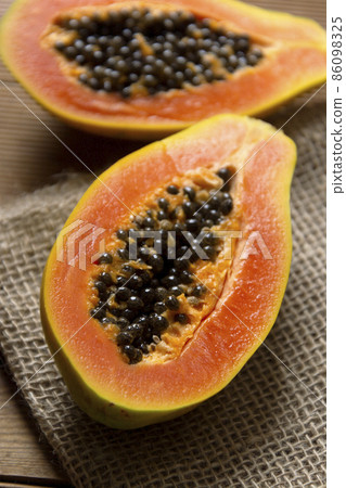 Sliced fresh papaya on wooden background, exotic fresh fruit Sliced fresh papaya on wooden background, exotic fresh fruit 86098325