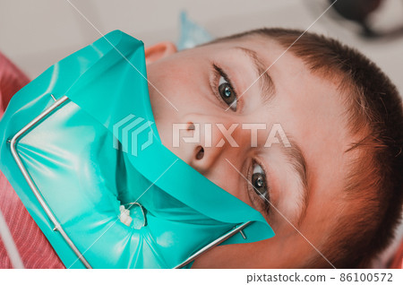 The dentist treats the child's tooth using a rubber dam. The dentist treats the child's tooth using a rubber dam. 86100572