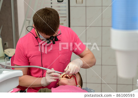 Dental treatment of a child, removal of caries with a drill, open mouth and ejector saliva. Dental treatment of a child, removal of caries with a drill, open mouth and ejector saliva. 86100593