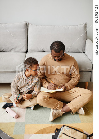 Father and Son Studying on Floor Father and Son Studying on Floor 86102423