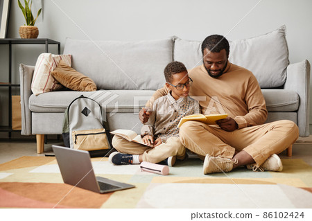 Father and Son Reading Book on Floor Father and Son Reading Book on Floor 86102424
