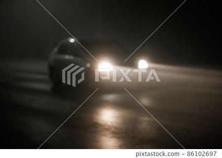 defocused photo of blurred car moving on empty night foggy road 86102697
