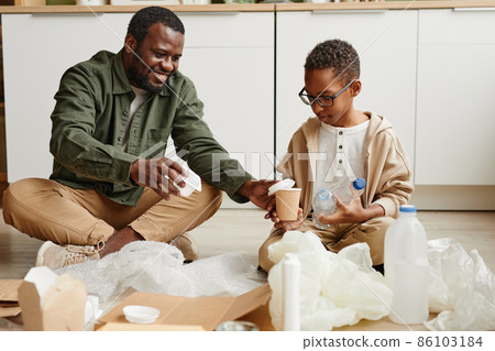 Father and Son Sorting Plastic at Home 86103184