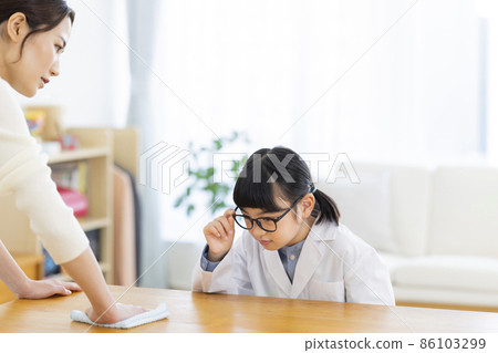 Housewife and girl in lab coat wiping the table Housewife and girl in lab coat wiping the table 86103299