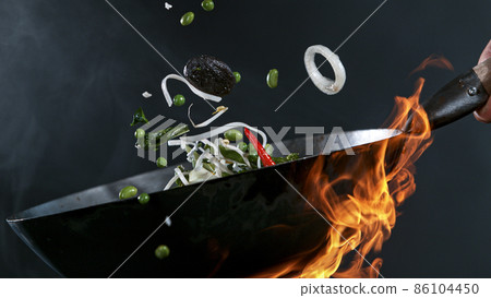 Freeze Motion of Wok Pan and Flying Ingredients in the Air. 86104450