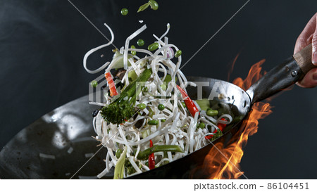Freeze Motion of Wok Pan and Flying Ingredients in the Air. Freeze Motion of Wok Pan and Flying Ingredients in the Air. 86104451