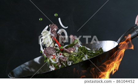 Freeze Motion of Wok Pan and Flying Ingredients in the Air. 86104452