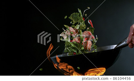 Freeze Motion of Wok Pan and Flying Ingredients in the Air. 86104456