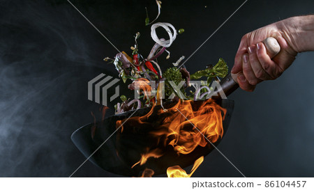 Freeze Motion of Wok Pan and Flying Ingredients in the Air. Freeze Motion of Wok Pan and Flying Ingredients in the Air. 86104457