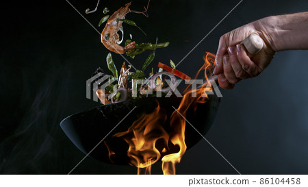 Freeze Motion of Wok Pan and Flying Ingredients in the Air. Freeze Motion of Wok Pan and Flying Ingredients in the Air. 86104458