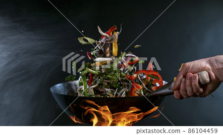 Freeze Motion of Wok Pan and Flying Ingredients in the Air. Freeze Motion of Wok Pan and Flying Ingredients in the Air. 86104459