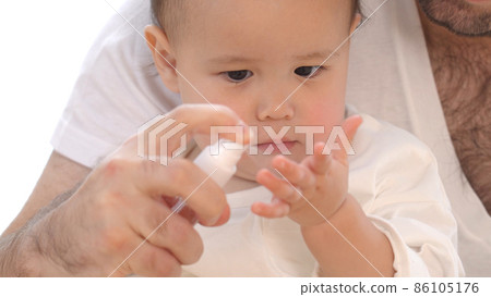Image of father spraying baby's hand 86105176