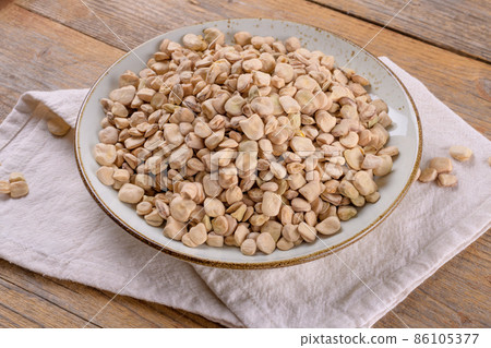 Dry raw cicerchia or indian pea on a ceramic plate with napkin on wooden background, close up 86105377