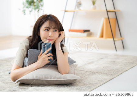 A woman looking at her smartphone in the living room A woman looking at her smartphone in the living room 86109965