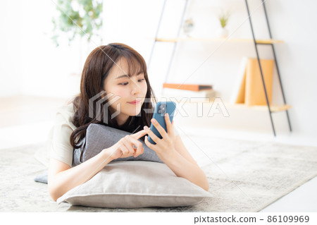 一個女人在客廳裡看著她的智能手機 86109969