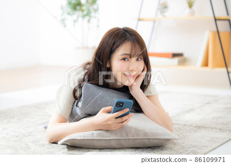 A woman looking at her smartphone in the living room A woman looking at her smartphone in the living room 86109971