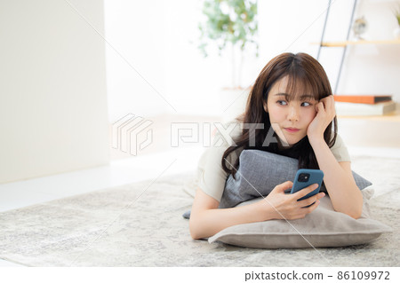 A woman looking at her smartphone in the living room 86109972