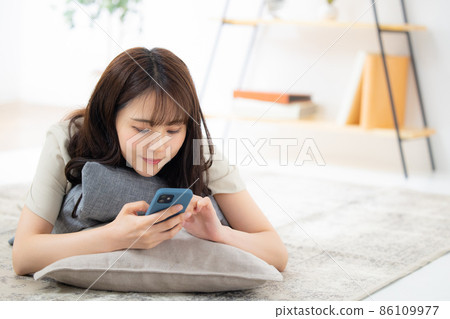 A woman looking at her smartphone in the living room 86109977