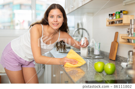 Young positive woman doing chores cleaning kitchen Young positive woman doing chores cleaning kitchen 86111802