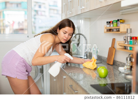Young positive woman doing chores cleaning kitchen 86111812