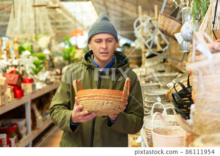 Man buying wicker basket in household goods store Man buying wicker basket in household goods store 86111954