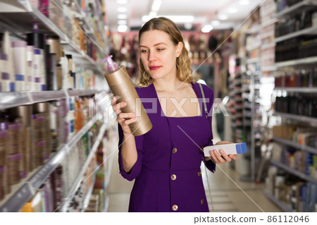 Smiling young woman choosing hair care products 86112046