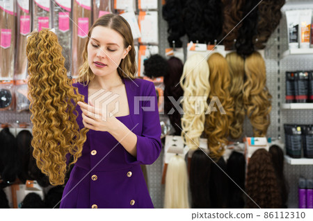 Girl choosing wigs from natural hair Girl choosing wigs from natural hair 86112310