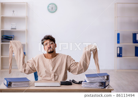 Crazy young man in straitjacket at the office 86113494