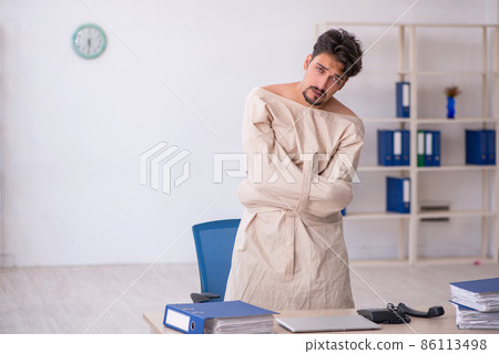Crazy young man in straitjacket at the office Crazy young man in straitjacket at the office 86113498