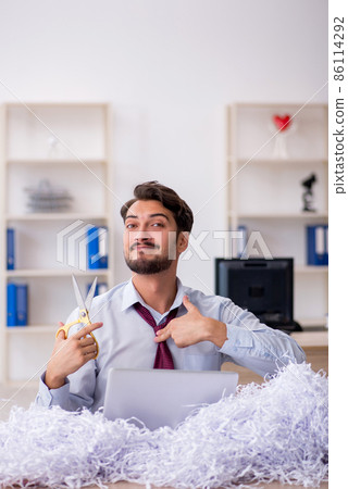 Young male employee and a lot of cut papers in the office 86114292