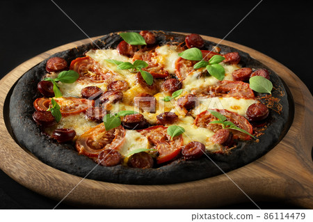 Black pizza with tomatoes, sausages, mozzarella and basil. Dough with healthy bamboo charcoal powder Black pizza with tomatoes, sausages, mozzarella and basil. Dough with healthy bamboo charcoal powder 86114479