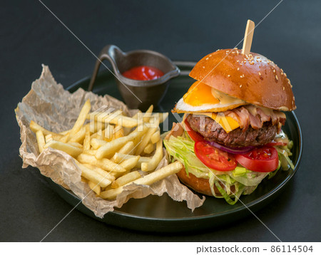 Delicious hamburger, served burger with french fries on a black background Delicious hamburger, served burger with french fries on a black background 86114504
