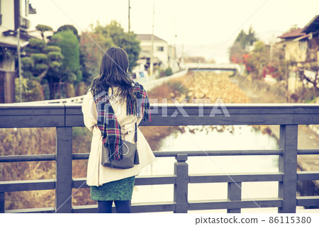 A woman looking at the river from the bridge A woman looking at the river from the bridge 86115380