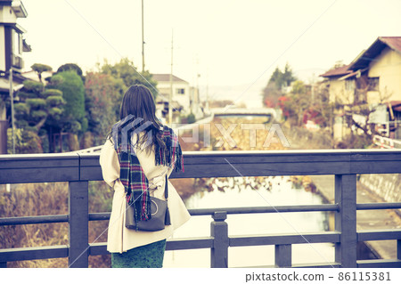 A woman looking at the river from the bridge A woman looking at the river from the bridge 86115381