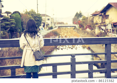A woman looking at the river from the bridge A woman looking at the river from the bridge 86115382