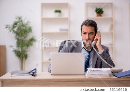 Young male employee unhappy with excessive work in the office 86116616