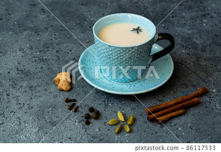 Indian tea masala chai. Seasoned chai masala tea with milk and spices on a dark gray background. 86117533