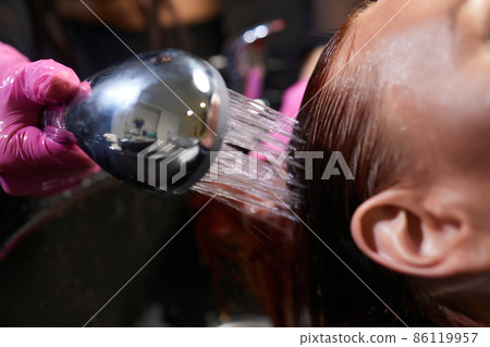 Hairdresser in beauty salon washes his client hair, before procedure of applying natural restoring ingredients and vitamins to hair and haircut. 86119957